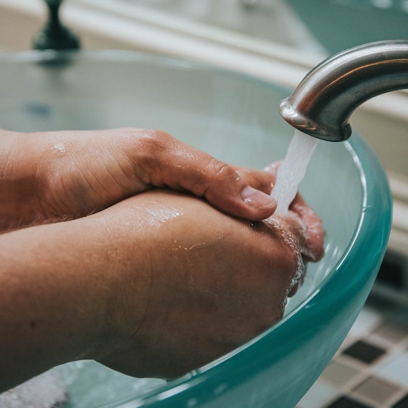 person holding stainless steel faucet